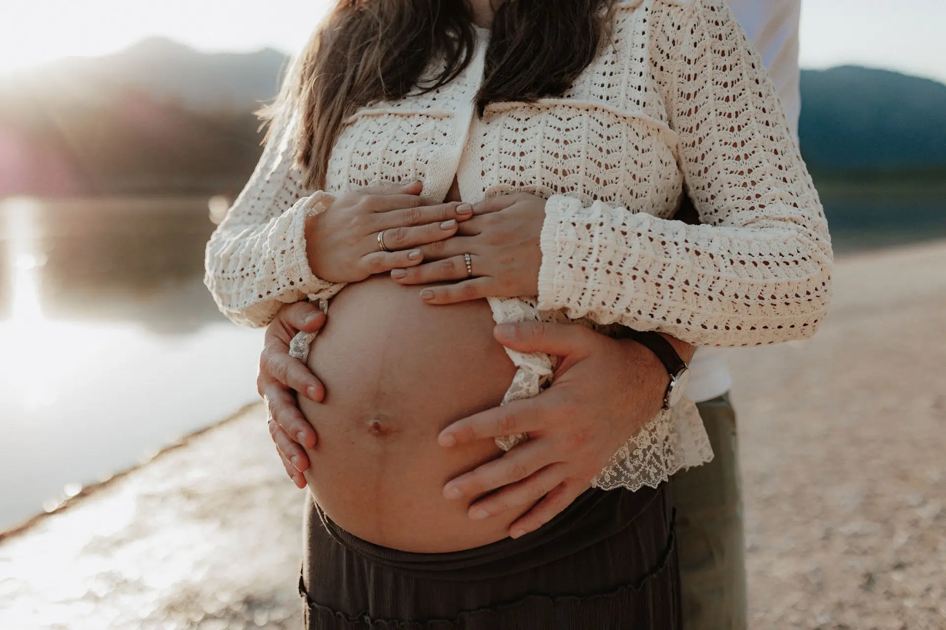 Babybauch im Gegenlicht an einem Bergsee
