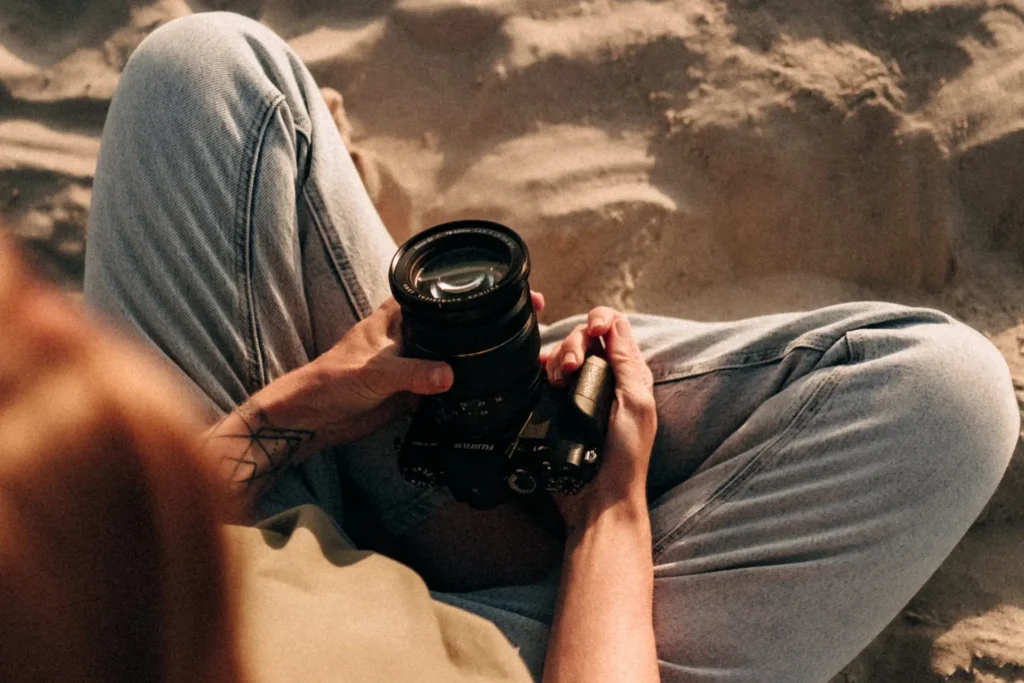 Haende halten eine Fujifilm-Kamera im warmen Abendlicht am Strand