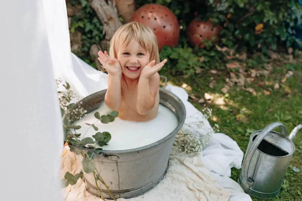 Lachendes Kleinkind im Milchbad im Garten