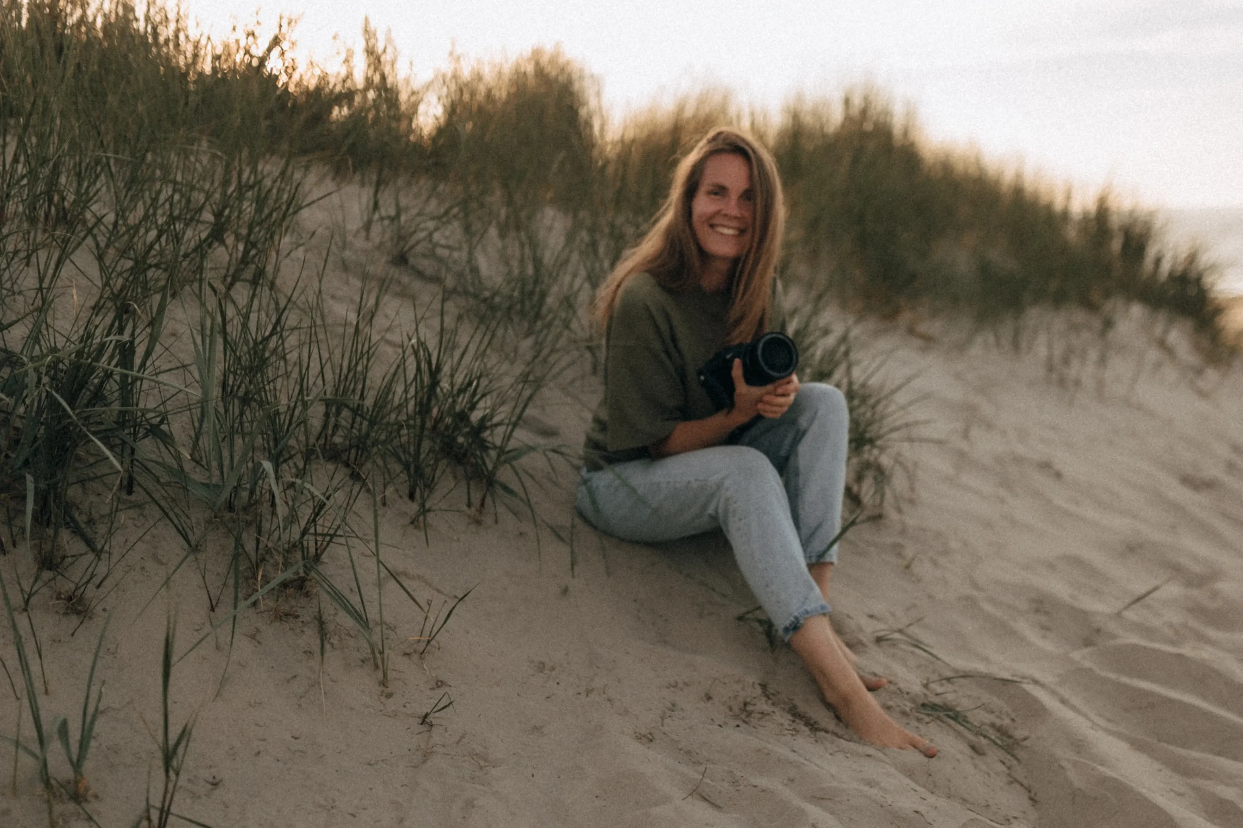 Linda sitzt mit ihrer Kamera am Strand