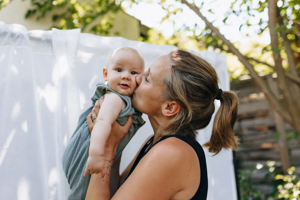 Mutter küsst ihr Baby im Garten